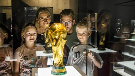Eine Familie bewundert den deutschen Siegerpokal der Fußball-WM von 2014 in der Schatzkammer des Dortmunder Fußballmuseums.