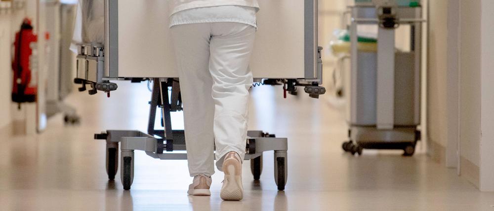 Eine Krankenpflegerin schiebt ein Krankenbett durch einen Krankenhausflur. 
