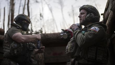 Ein ukrainischer Soldat der Asow-Brigade, bekannt unter dem Rufnamen Chaos, rechts, trägt eine Mörsergranate, während er auf einen Feuerbefehl wartet. 
