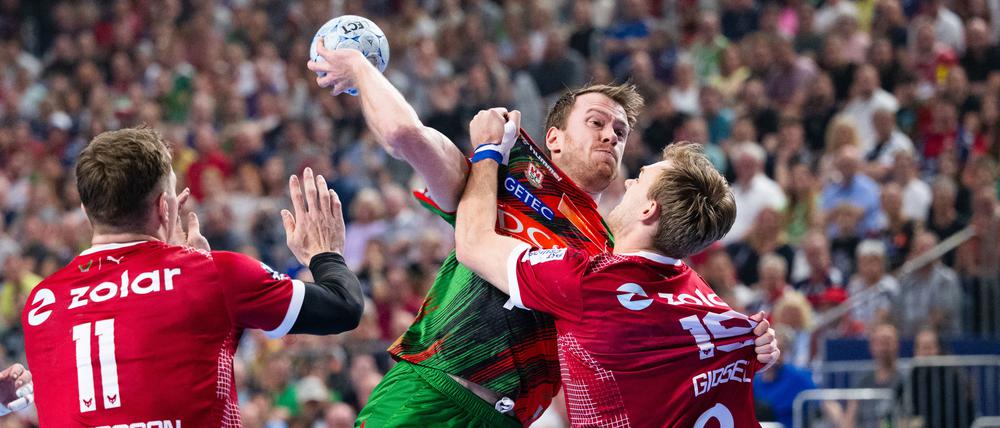 Im Nahkampf. Berlins Lasse Andersson (l) und Mathias Gidsel (r) versuchen Magdeburgs Felix Claar am Wurf zu hindern. 