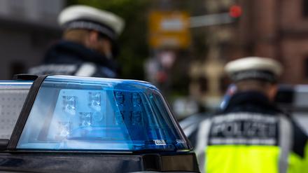  Zwei Polizeibeamte stehen zwischen zwei Einsatzfahrzeugen der Polizei. 