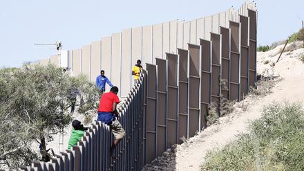 Italien, Lampendusa: Geflüchtete klettern über einen Zaun auf der Insel Lampedusa.
