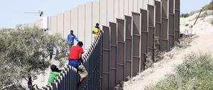 Italien, Lampendusa: Geflüchtete klettern über einen Zaun auf der Insel Lampedusa.