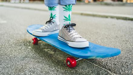 Junge Frau mit Marihuana-Socken auf einem Skateboard.