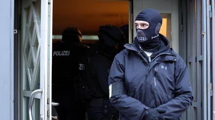 Einsatzkräfte der Polizei stehen bei einer Durchsuchung im Eingangsbereich eines Gebäudes. (Symbolbild)
