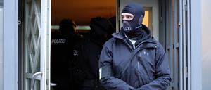 Einsatzkräfte der Polizei stehen bei einer Durchsuchung im Eingangsbereich eines Gebäudes. (Symbolbild)