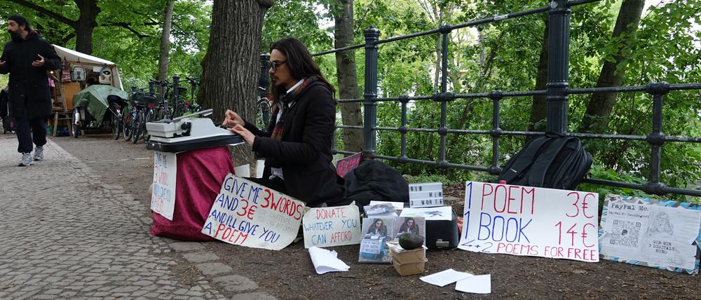 Der Künstler Dan Sigurd schreibt am Landwehrkanal Drei-Wort-Gedichte für drei Euro.