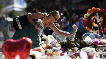 Eine Frau legt am Dienstag, 16. April 2024, im Einkaufszentrum Westfield Bondi Junction in Sydney Blumen nieder. 