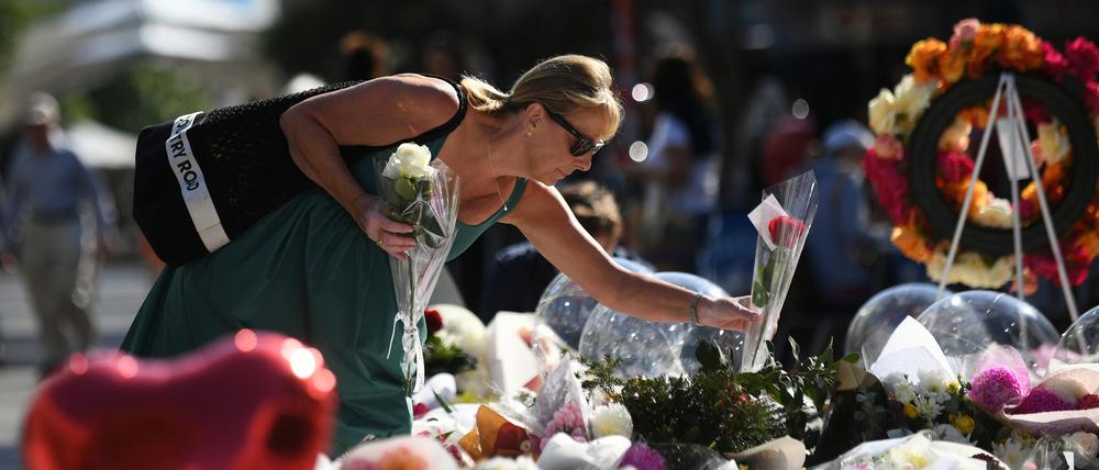 Eine Frau legt am Dienstag, 16. April 2024, im Einkaufszentrum Westfield Bondi Junction in Sydney Blumen nieder.