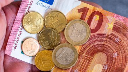 Geldscheine und Euro-Münzen mit dem Wert von 12,41 Euro liegen auf einer Hand – der derzeitige Mindestlohn in Deutschland.