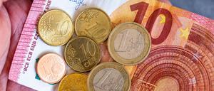Geldscheine und Euro-Münzen mit dem Wert von 12,41 Euro liegen auf einer Hand – der derzeitige Mindestlohn in Deutschland.