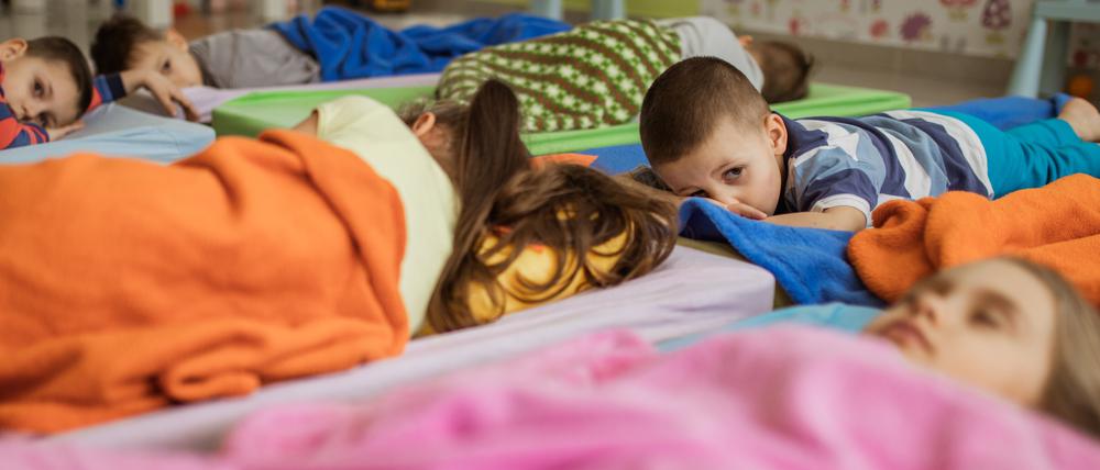 Eine Gruppe von Kindern macht Mittagsschlaf.