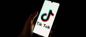 This photograph taken on April 19, 2024 shows a man holding a smartphone displaying the logo of Chinese social media platform Tiktok in an office in Paris (Photo by Antonin UTZ / AFP)