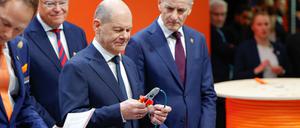 Bundeskanzler Olaf Scholz (SPD) schneidet ein Stück einer Datenleitung aus einem nachhaltigen, biobasierten Mantelmaterial zur industriellen Anwendung ab am Stand von Lapp auf der Hannover Messer. 