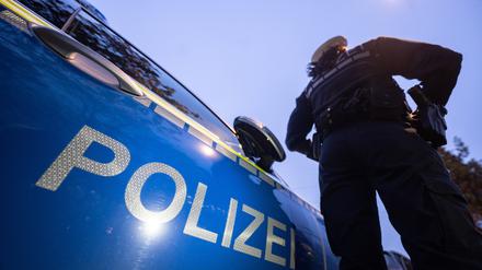 Eine Polizistin steht neben einem Polizeifahrzeug. 