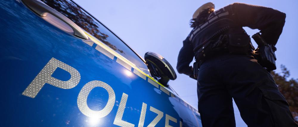 Eine Polizistin steht neben einem Polizeifahrzeug.