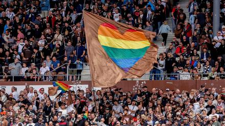 Fans schwenken Regenbohnenfahnen auf der Tribüne von St. Pauli.