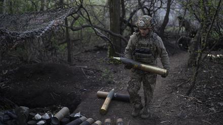 Ein ukrainischer Soldat trägt eine Granate für eine Haubitze an der Front.