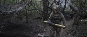 Ein ukrainischer Soldat der Asow-Brigade trägt eine Granate für eine Gebirgshaubitze Modell 56 an der Frontlinie in Richtung Kreminna, Region Donezk.