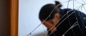 Eine Frau sitzt neben einem gesprungenen Spiegel auf einem Bett und hält ihren Kopf in den Händen (gestellte Szene). Die EU will Gewalt gegen Frauen den Kampf ansagen.