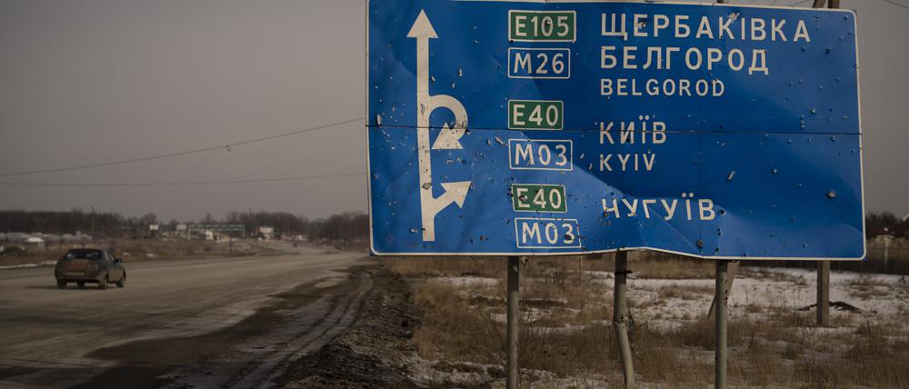 Ein Auto fährt an einem von Kugeln und Granatsplittern beschädigten Straßenschild auf der Straße zur russischen Stadt Belgorod vorbei.