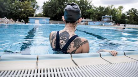 Ein Badegast pausiert am Schwimmbeckenrand im Sommerbad Kreuzberg. +++ dpa-Bildfunk +++