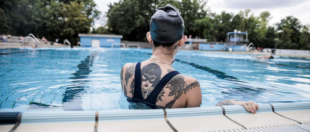 Ein Badegast pausiert am Schwimmbeckenrand im Sommerbad Kreuzberg. +++ dpa-Bildfunk +++