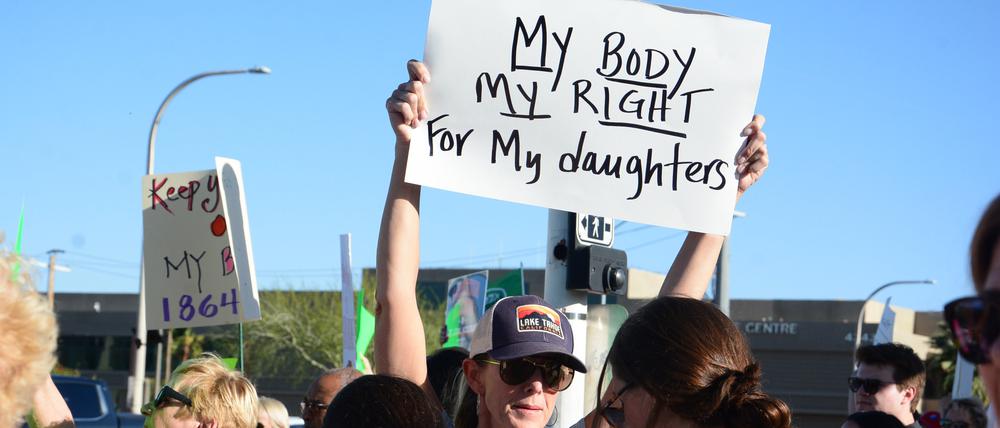 14.04.2024, USA, Scottsdale: Eine Demonstrantin hält ein Schild während einer Kundgebung gegen das Abtreibungsurteil. Hunderte von Menschen gingen am Sonntag auf die Straße, nachdem der Oberste Gerichtshof von Arizona am Dienstag ein fast vollständiges Abtreibungsverbot aus dem Jahr 1864 wieder in Kraft gesetzt hatte. Foto: Xuguang Sui/XinHua/dpa +++ dpa-Bildfunk +++