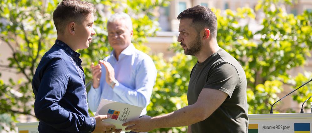 Präsident Selenskyj händigt einem 14-Jährigen einen Reisepass aus.