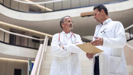 Doctor discussing with colleague over report document in hospital model released, Symbolfoto property released, JOSEF12725