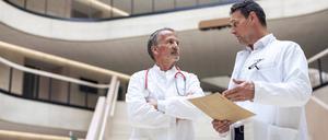 Doctor discussing with colleague over report document in hospital model released, Symbolfoto property released, JOSEF12725
