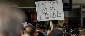 27.04.2024, Hamburg: Teilnehmer einer Islamisten-Demo halten ein Plakat mit der Aufschrift „Kalifat ist die Lösung“ in die Höhe. 