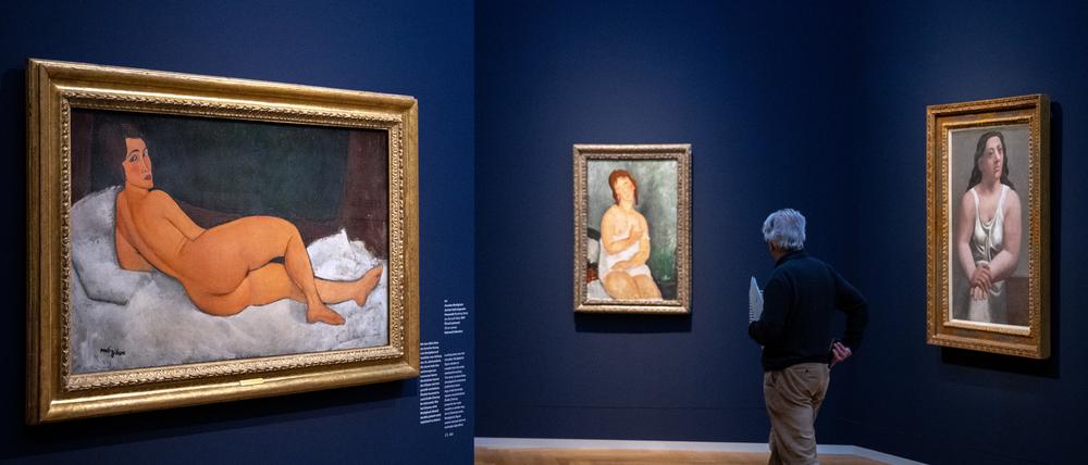 25.04.2024, Brandenburg, Potsdam: Ein Mann geht nach der Pressekonferenz zur Ausstellung «Modigliani. Moderne Blicke» im Museum Barberini an den Bildern (l-r) „Auf der Seite liegender Frauenakt (2017, Öl auf Leinwand) und „Junge Frau im Unterkleid, weiblicher Halbakt“ (1918, Öl auf Leinwand) von Amedeo Modigliani sowie „Sitzende Frau im Hemd“ (1921, Öl auf Leinwand) von Pablo Picasso vorbei. 