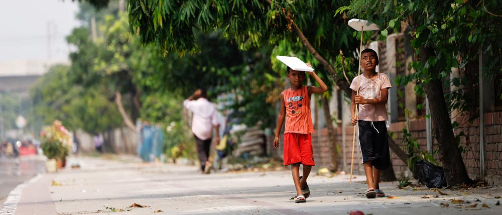 Children hold cork sheets to cover them from the sun while walking along a street during a countrywide heatwave in Dhaka, Bangladesh, April 28, 2024. REUTERS/Mohammad Ponir Hossain