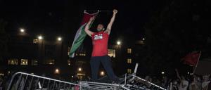 Ein Student der George Washington University schwenkt eine palästinensische Flagge, während er auf einer Polizeisperre steht.