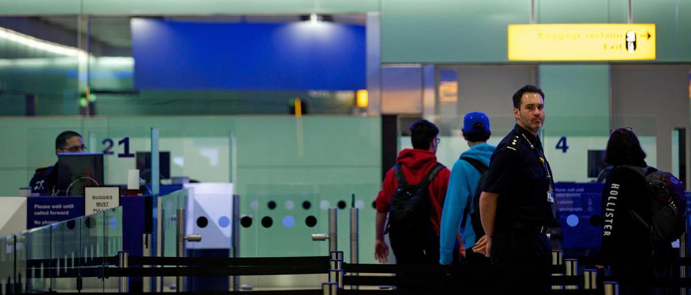 Grenzbeamte stehen am Flughafen London-Heathrow unter einem Schild mit der Aufschrift „UK Border“ (Grenze des Vereinigten Königreiches).