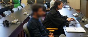 Der Angeklagte (vorne) sitzt zu Beginn des Prozesses wegen Geiselnahme, Entziehung Minderjähriger, vorsätzlicher Körperverletzung und Waffendelikten im Sitzungssaal im Strafjustizgebäude.