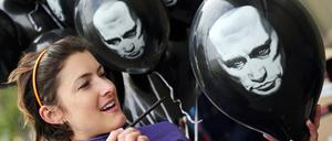 Anna Büchling zersticht am Donnerstag (26.04.2012) vor der russischen Botschaft in Berlin einen Luftballon mit dem Bild von Putin. In den Ballons befinden sich Zettel mit einer Petition an Wladimir Putin, mit der Aufforderung eine freie Berichterstattung in seinem Land zuzulassen. Foto: Hannibal dpa/lbn ++ +++ dpa-Bildfunk +++