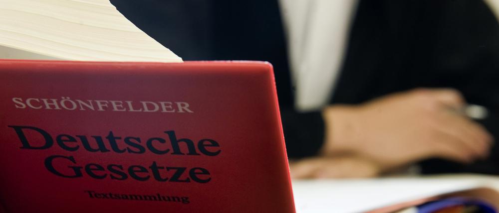 Ein Anwalt sitzt hinter der aufgeschlagenen „Schönfelder Textsammlung Deutsche Gesetze“ in einem Gericht (Symbolbild).