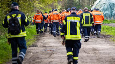 Einsatzkräfte der Feuerwehr gehen auf der Suche nach Arian eine Straße im Landkreis Stade entlang. 