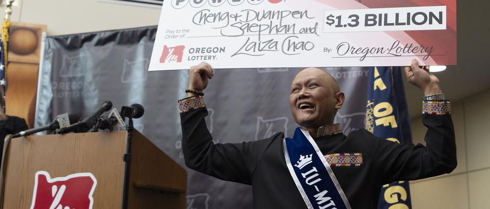 29.04.2024, USA, Salem: Cheng „Charlie“ Saephan hält einen übergroßen Scheck über seinen Kopf, nachdem er auf einer Pressekonferenz in der Lotteriezentrale von Oregon in Salem, Oregon, bekannt gegeben hat, dass er einer der Gewinner des Powerball-Jackpots in Höhe von 1,3 Milliarden US-Dollar (etwa 1,21 Milliarden Euro) ist.