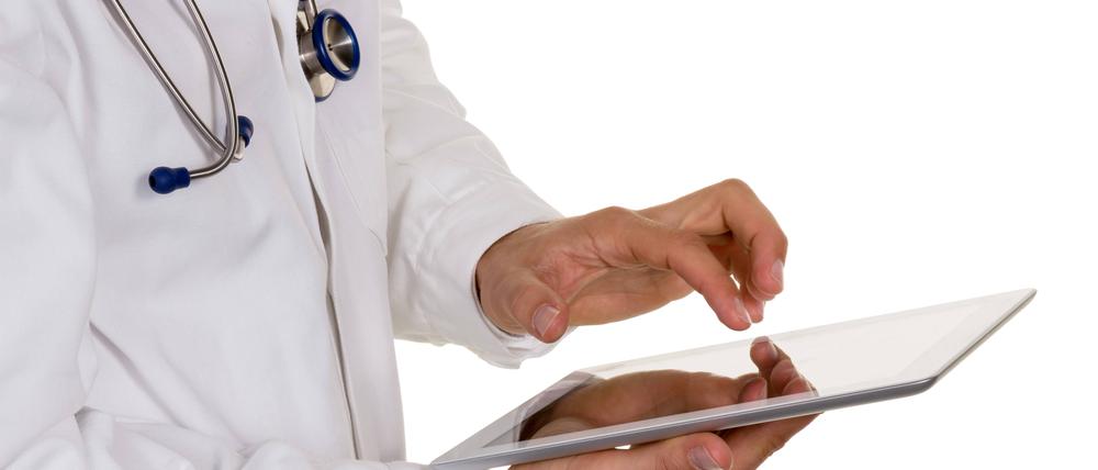 Ein junger Arzt mit Stethoskop und Tablet.