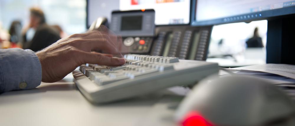 Ein Mann tippt einem Büro auf einer Tastatur. 