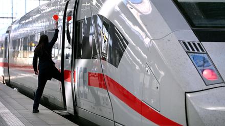 Zugbegleiterin signalisiert dem Lokführer mit roter Kelle, dass der ICE-Zug zur Abfahrt bereit ist.