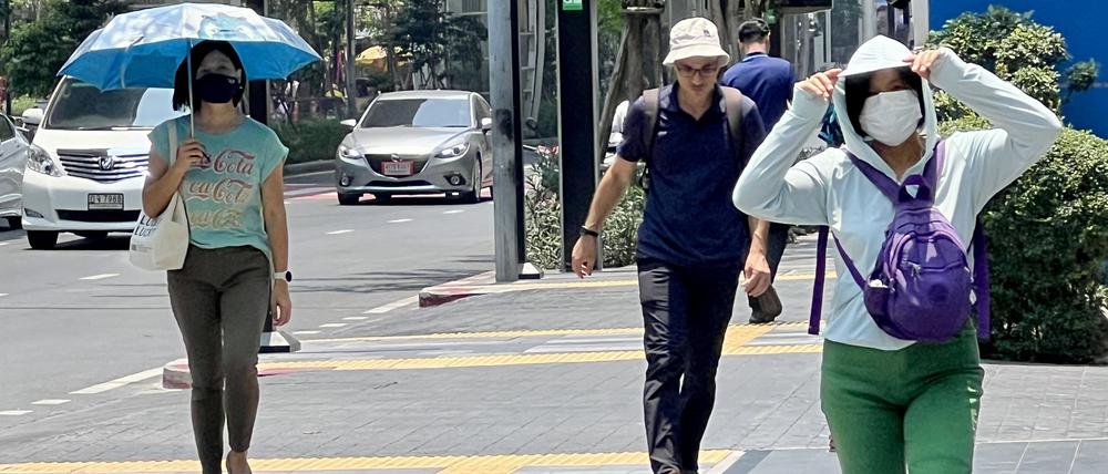 Menschen auf der Silom Road in Bangkok versuchen, sich vor der Hitze zu schützen. 
