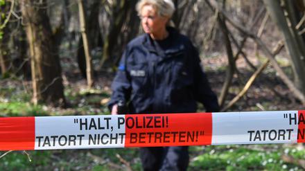 Symbolbild: Eine Polizeibeamtin läuft in einem Waldgebiet bei Brieselang hinter einem Absperrband der Polizei entlang. «