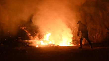Ein Anwohner versucht in der Nacht zum 1. Mai 2024 in der Nähe des Dorfes Lubhu im Distrikt Lalitpur am Stadtrand von Kathmandu einen Flächenbrand zu löschen.