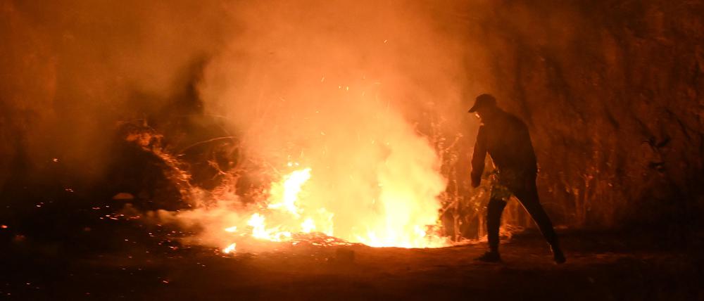 Ein Anwohner versucht in der Nacht zum 1. Mai 2024 in der Nähe des Dorfes Lubhu im Distrikt Lalitpur am Stadtrand von Kathmandu einen Flächenbrand zu löschen.