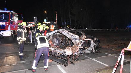 Rettungskräfte stehen am Wrack eines zerstörten Autos nach einem Unfall an einem Bahnübergang. 