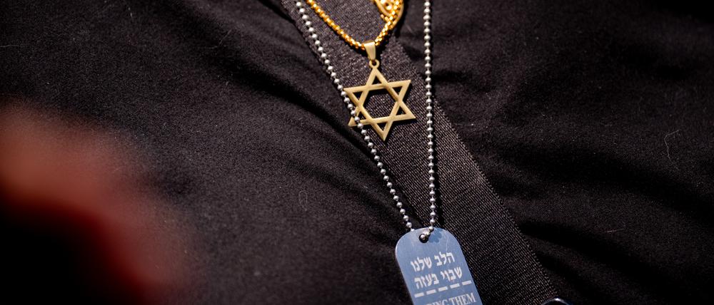 Eine Frau trägt das Davidstern-Symbol und eine weitere Halskette mit der Aufschrift „Bring Them Home Now!“ während einer Kundgebung gegen den Antisemitismus auf dem Campus der George Washington University